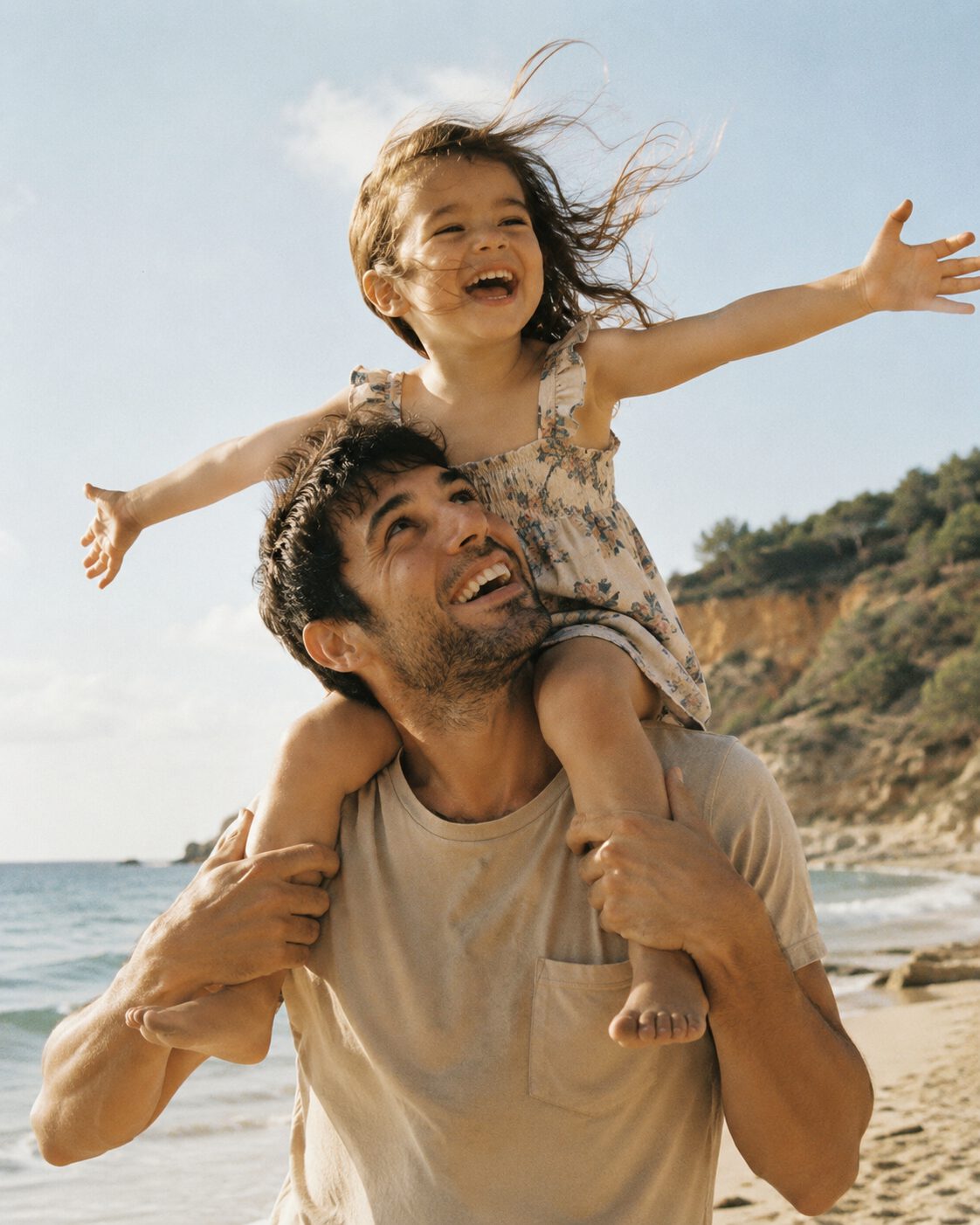 A father carrying his laughing daughter at the beach